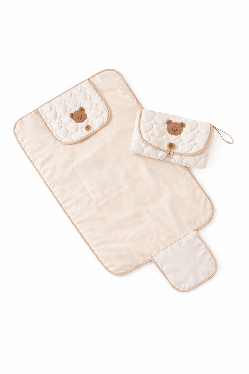 Beige quilted baby changing mat with bear face design on a white background