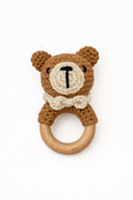 Crocheted teddy bear rattle with wooden ring on a white background