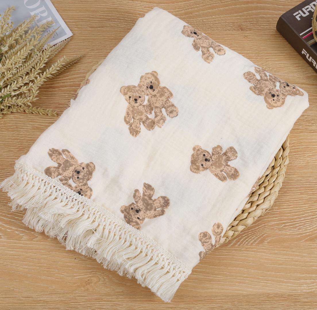 White blanket with teddy bear patterns on a wooden surface