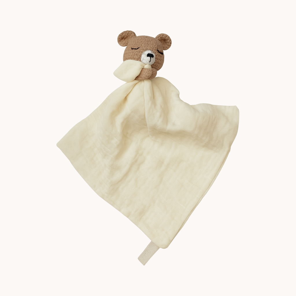 Bear-shaped plush toy with a cream blanket on a white background