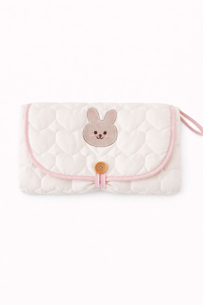 A closed, light pink, bunny themed diaper changing pad