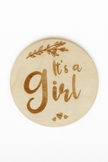 Wooden round sign with 'It's a Girl' text on a white background