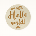 Round beige plaque with 'Hello world!' text and leaf design on a white background